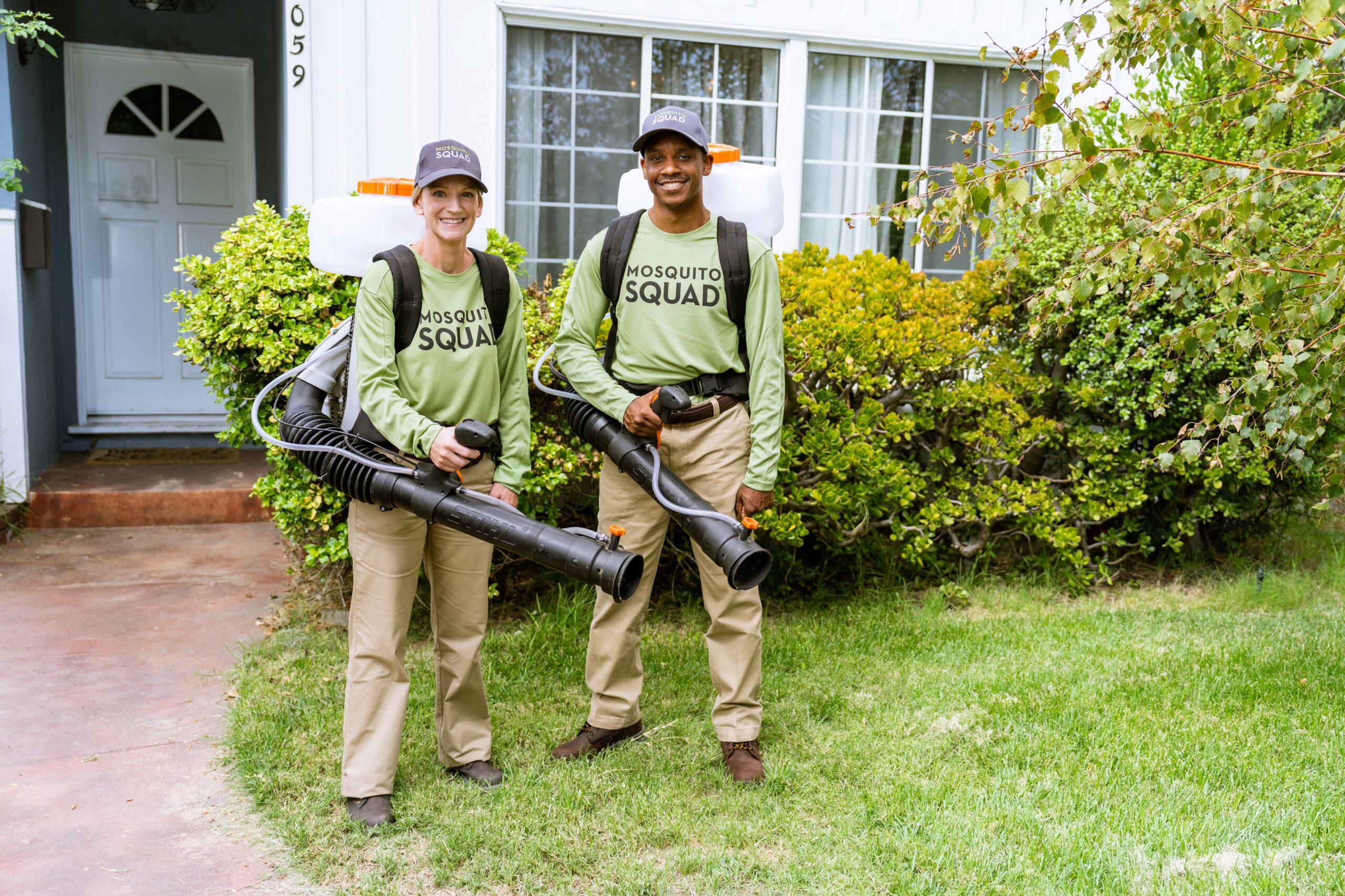 Techs spraying mosquitos in a backyard