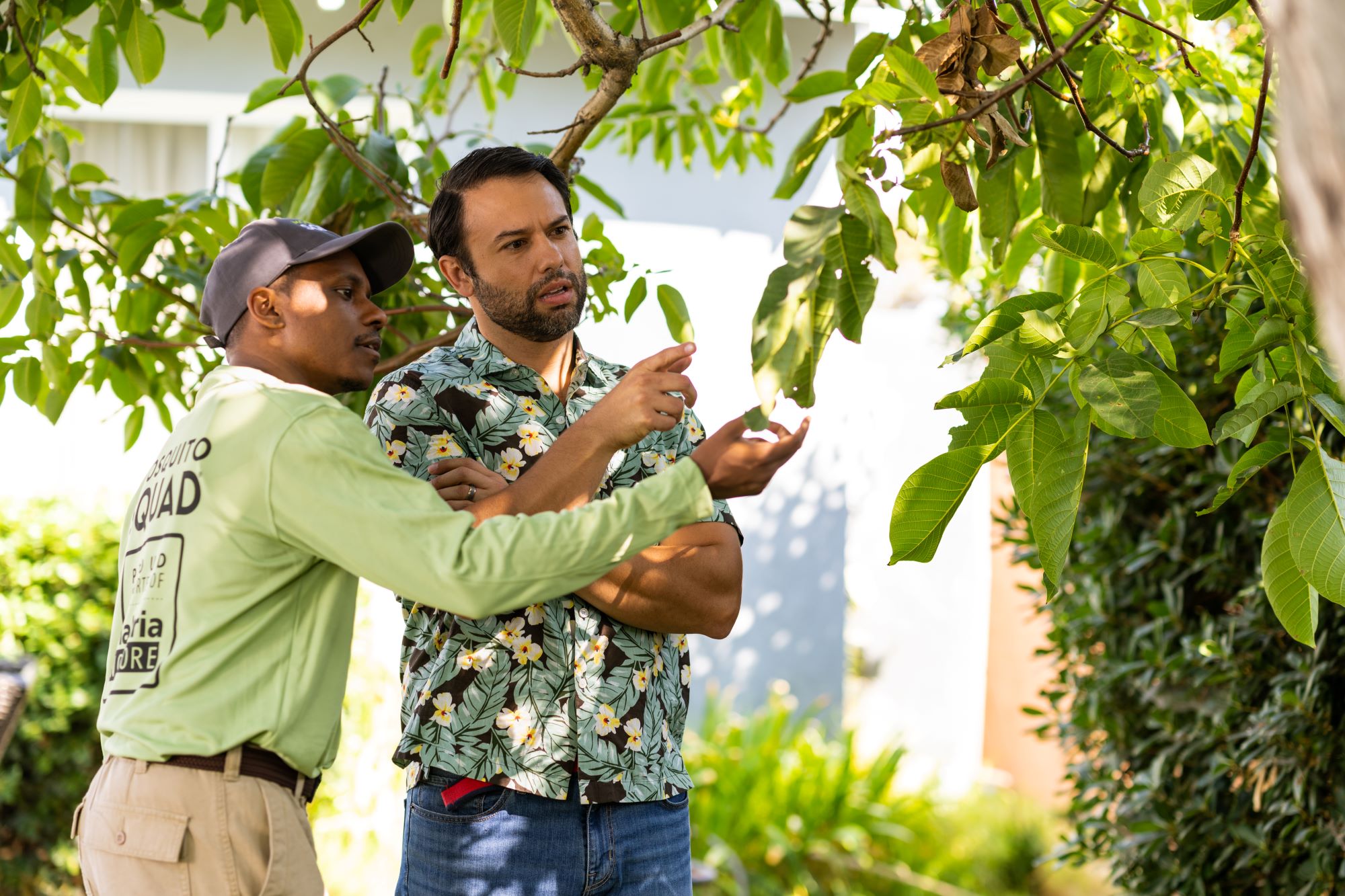 Mosquito Squad pest control business owner inspecting leaves with a homeowner.