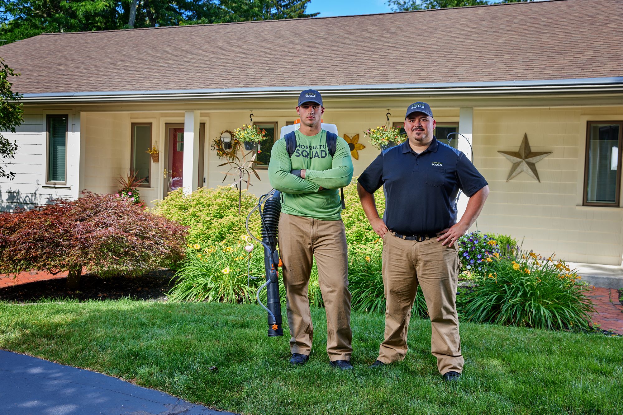 Pest control business owner and tech standing in front yard.