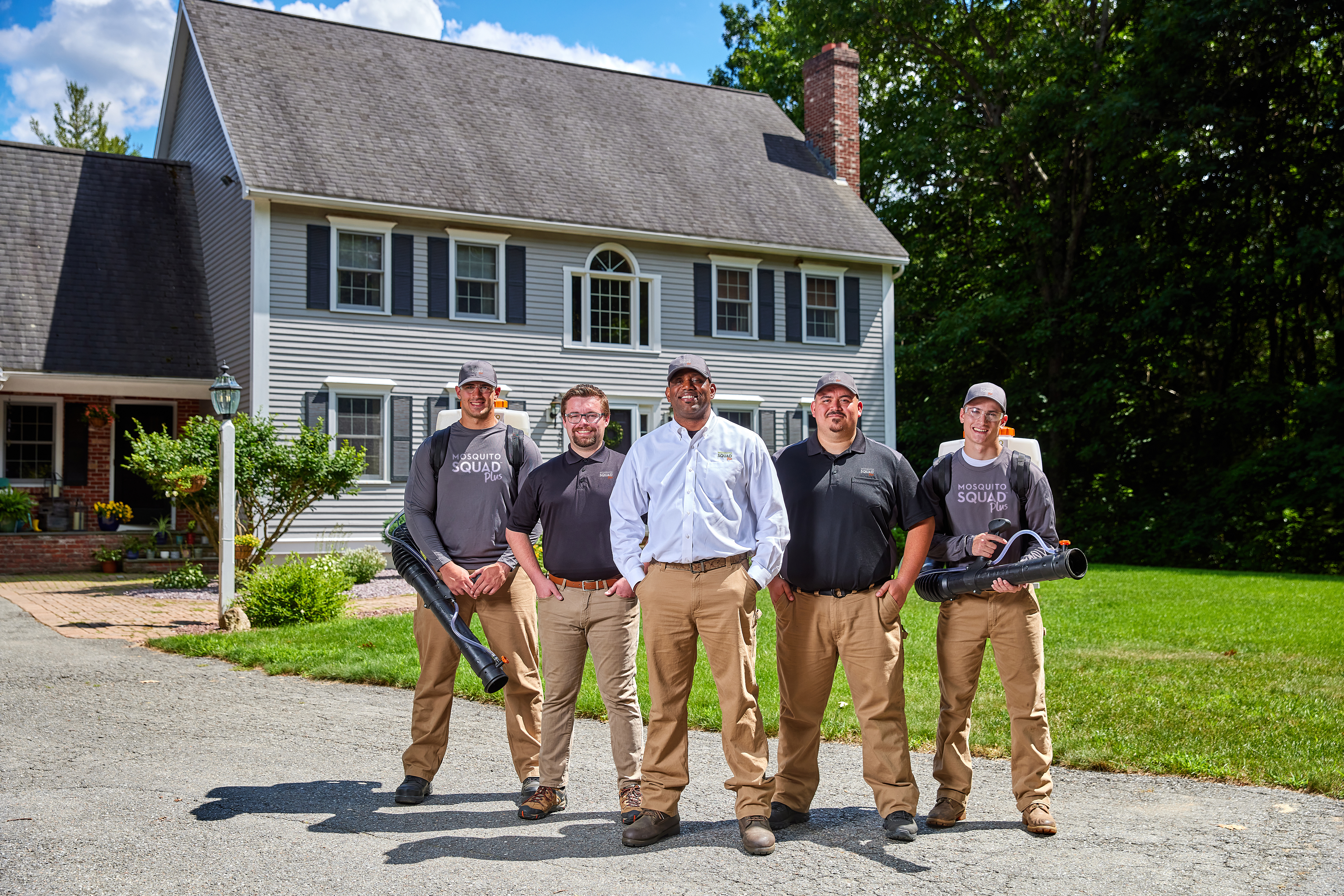 Mosquito Squad owner and  his tech stand proudly outside a home